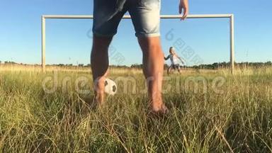 快乐的父亲和女儿在绿茵场上用足球大门打球。 快乐的家庭踢足球。